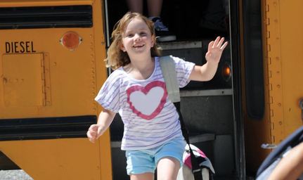 girl smiling by school bus
